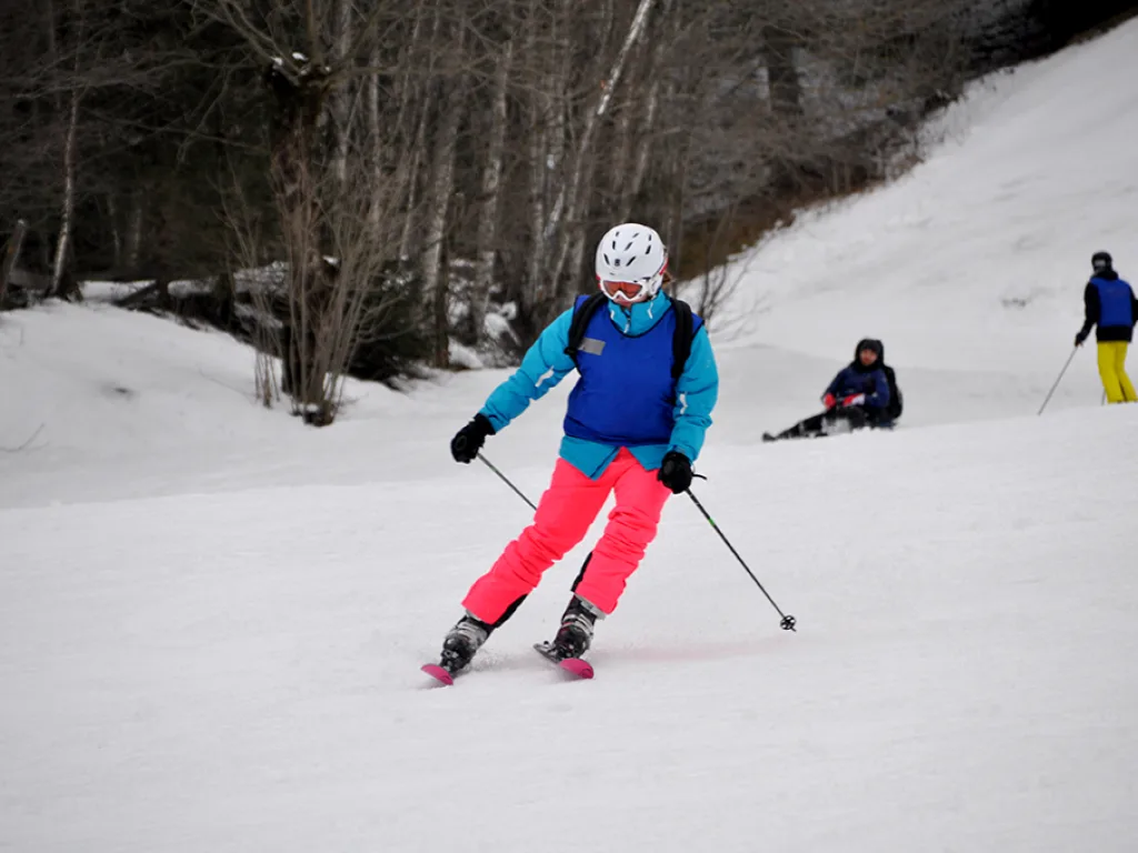 Skifahrerin in pinker Hose zieht einen Schwung.